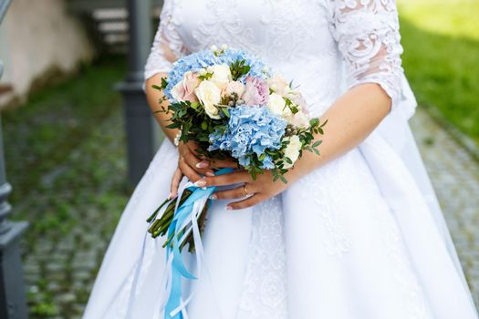 Beautiful wedding bouquet of flowers in the hands of the newlyweds