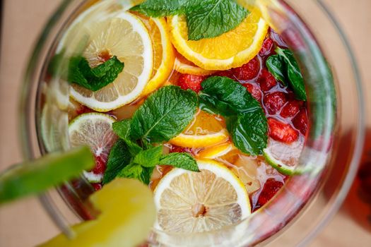 Refreshing lemonade with fresh fruit orange lemon cherry and mint leaves. Delicious non-alcoholic fruit cocktail in a jug