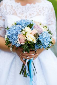 Beautiful wedding bouquet of flowers in the hands of the newlyweds