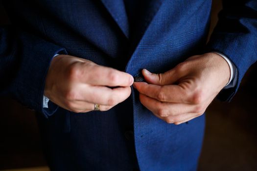 man puts on a suit on the wedding day
