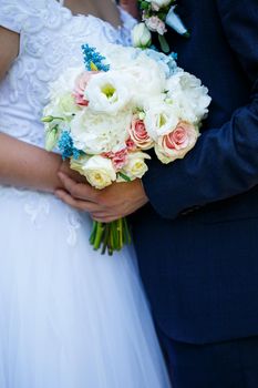 Beautiful wedding bouquet of flowers in the hands of the newlyweds