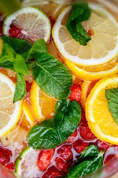 Refreshing lemonade with fresh fruit orange lemon cherry and mint leaves. Delicious non-alcoholic fruit cocktail in a jug