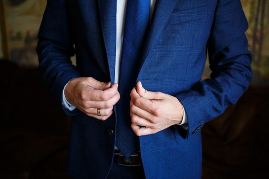 man puts on a suit on the wedding day