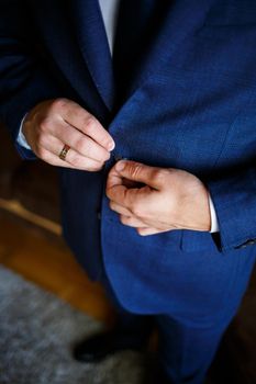 man puts on a suit on the wedding day