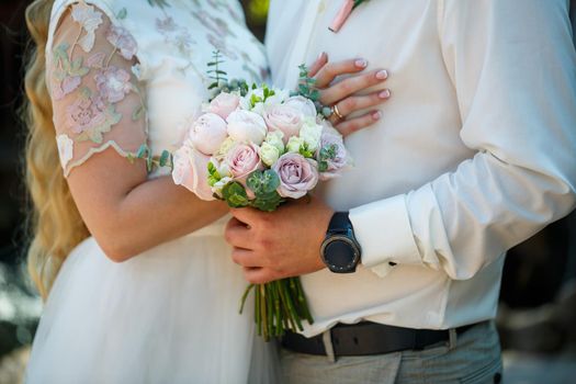 Beautiful wedding bouquet of flowers in the hands of the newlyweds