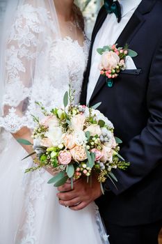 Beautiful wedding bouquet of flowers in the hands of the newlyweds