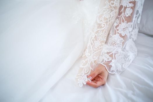 The bride holds a white dress in her hands on the wedding day.