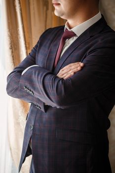 Stylish man groom buttoning a button on his jacket