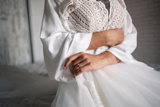 The bride holds a white dress in her hands on the wedding day.
