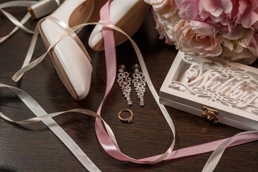Wedding shoes for the bride. White high-heeled shoes near wedding rings, wedding jewelry. Marriage concept