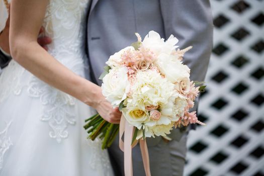 Beautiful wedding bouquet of flowers in the hands of the newlyweds