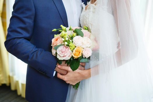 Beautiful wedding bouquet of flowers in the hands of the newlyweds