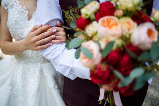 Beautiful wedding bouquet of flowers in the hands of the newlyweds