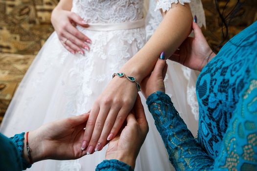 bride puts on wedding jewelry on the wedding day