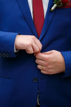 man puts on a suit on the wedding day