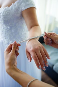 bride puts on wedding jewelry on the wedding day