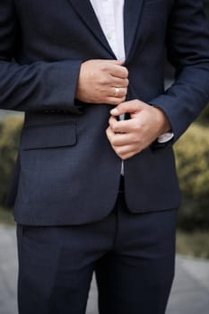 Stylish man groom buttoning a button on his jacket
