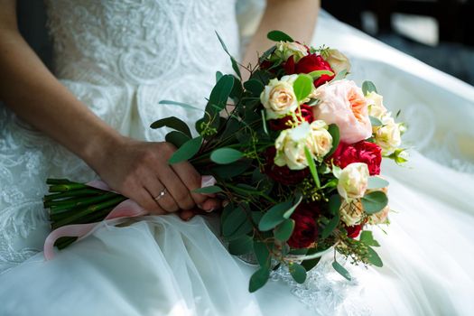Beautiful wedding bouquet of flowers in the hands of the newlyweds