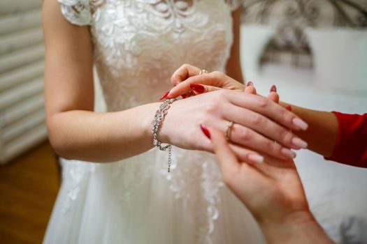 bride puts on wedding jewelry on the wedding day