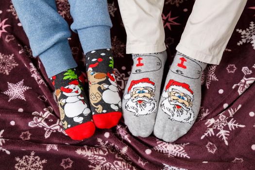 Couple relax. Two pair of feet in colorful ornamented Christmas socks over blurred Xmas room background, selective focus
