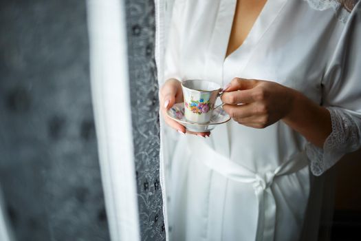 Girl bride drinks coffee on wedding morning