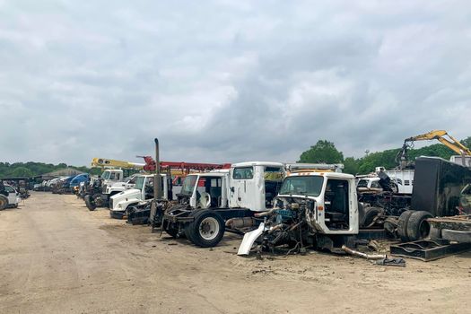 A lot of big abandoned broken trucks in a junkyard, wrecked trucks with damaged parts are in a car dump, automobile recycling after accidents