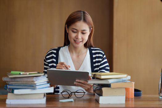 Back to school concept. Young college woman reading book at library.