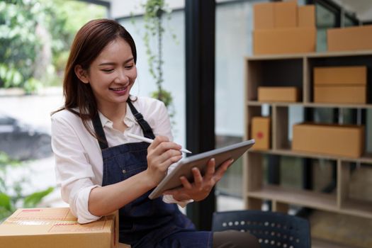 Attractive Asian entrepreneur business woman checking order by tablet.