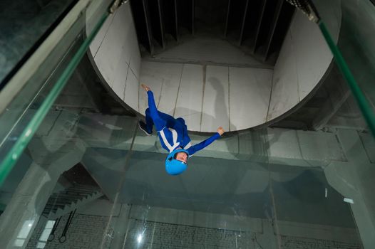 A man in overalls and a protective helmet enjoys flying in a wind tunnel. Free fall simulator.