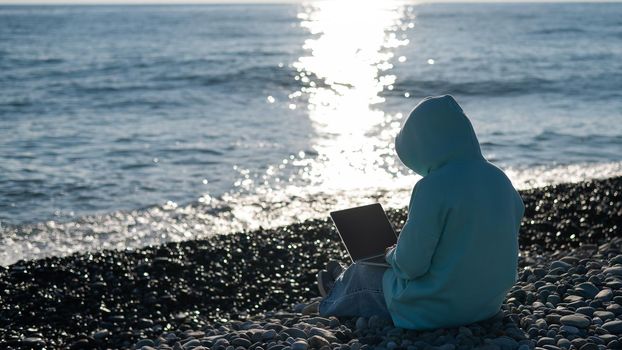 Caucasian woman working freelance on laptop on the beach