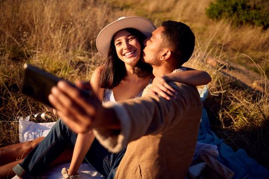 Lets capture this moment. a young couple enjoying the sunset and taking a selfie outside in nature