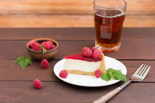 Raspberry pie (cheesecake) made from fresh raspberries with tea on a wooden background.