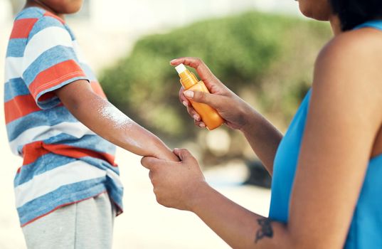 We have to protect your skin. a mother applying sunscreen to her son at the beach