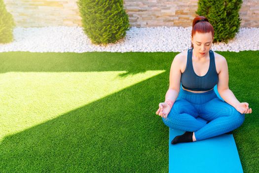 woman practicing meditation in the open air, relaxation exercises, doing the lotus posture. copy space. concept of health and well-being. natural outdoor light.