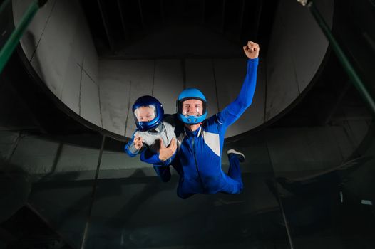 A man teaches a boy to fly in a wind tunnel. Lack of gravity