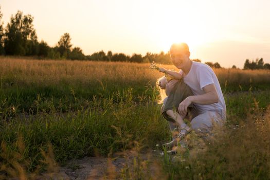 Dad and his blonde daughter are walking and having fun in a chamomile field. The concept of Father's Day, family and nature walks.