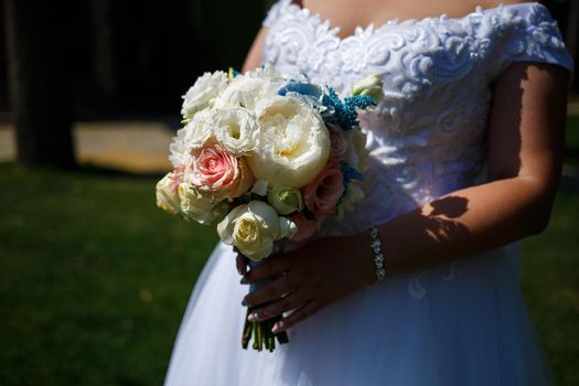 Beautiful wedding bouquet of flowers in the hands of the newlyweds
