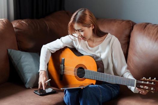 A beginner woman playing acoustic guitar lesson.