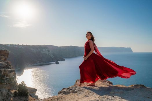 A woman in a red flying dress fluttering in the wind, against the backdrop of the sea