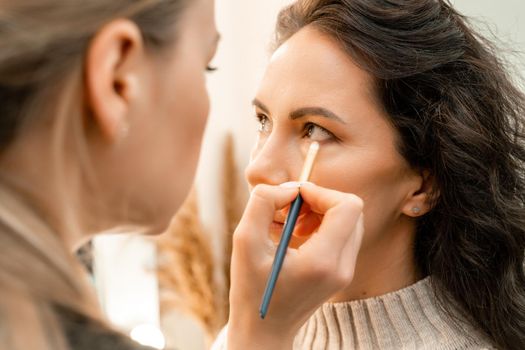 Make-up artist makes a professional make-up of a young woman in the studio