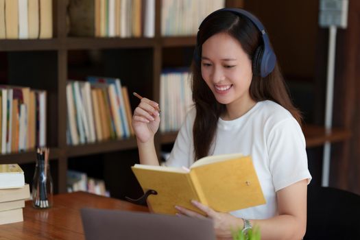 Back to school concept. Young college woman using laptop at library.