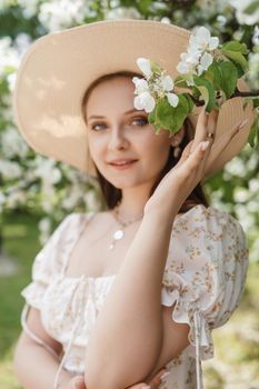 An attractive long-haired woman walks in the spring in the park of blooming apple trees. Spring portrait of a woman