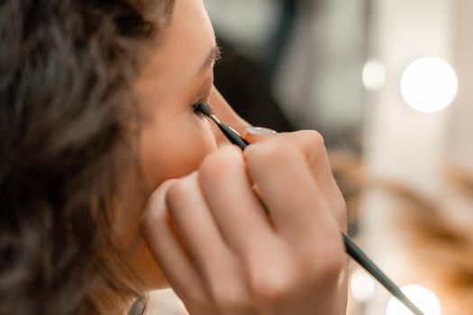 Make-up artist makes a professional make-up of a young woman in the studio