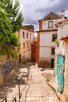 Stairs with railings and walls with street art in the narrow streets of the historic city of Coimbra in Portugal