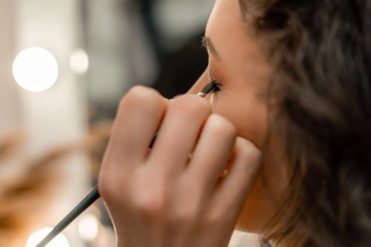 Make-up artist makes a professional make-up of a young woman in the studio