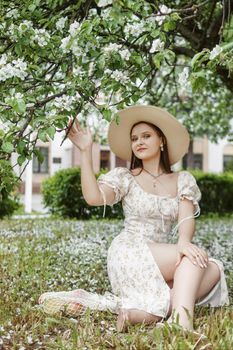 An attractive long-haired woman walks in the spring in the park of blooming apple trees. Spring portrait of a woman