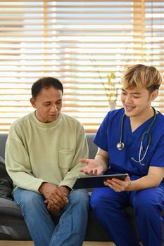Smiling asian doctor talking and explaining test result to elderly patient during home visit. Elderly healthcare concept.