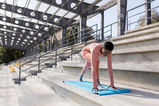 African American woman doing yoga near the stadium in the morning, active lifestyle performs fitness exercises