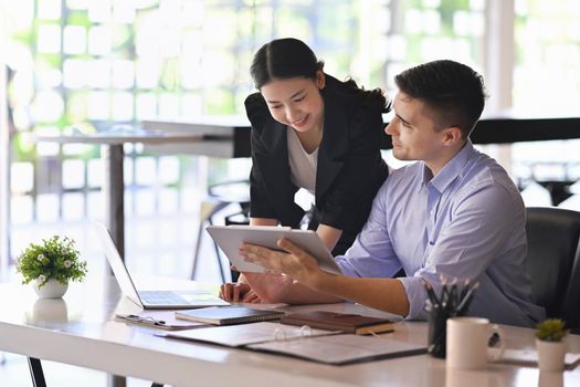 Handsome businessman holding digital tablet and explaining information to his colleague.