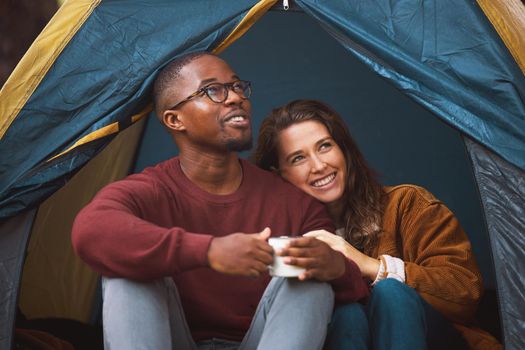 Nothing says romance like a tent, chirping birds and bae. a young couple drinking coffee while sitting in their tent